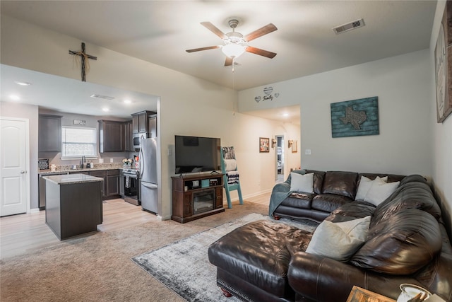 carpeted living room with sink and ceiling fan