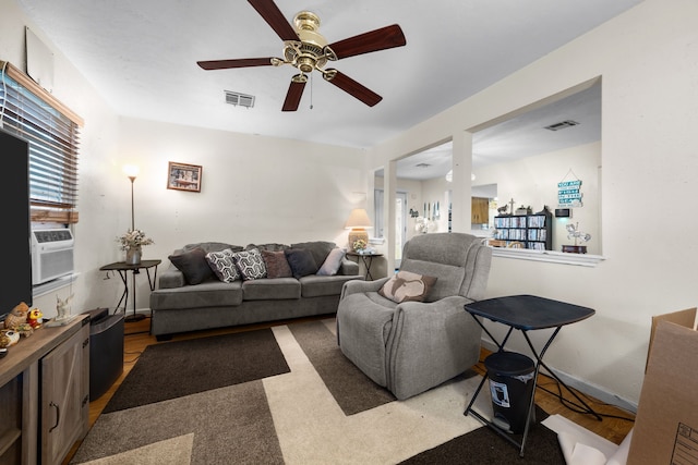 living room with cooling unit, a ceiling fan, visible vents, and baseboards