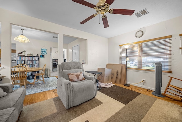 living room with visible vents, baseboards, wood finished floors, and a ceiling fan