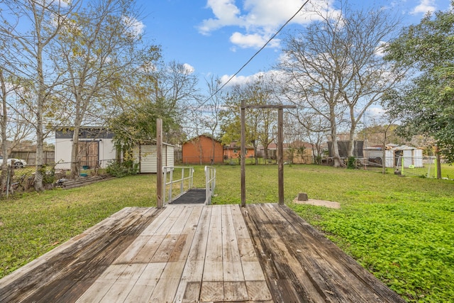 wooden terrace featuring a storage unit and a lawn