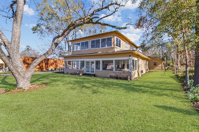 rear view of house featuring a lawn and a sunroom