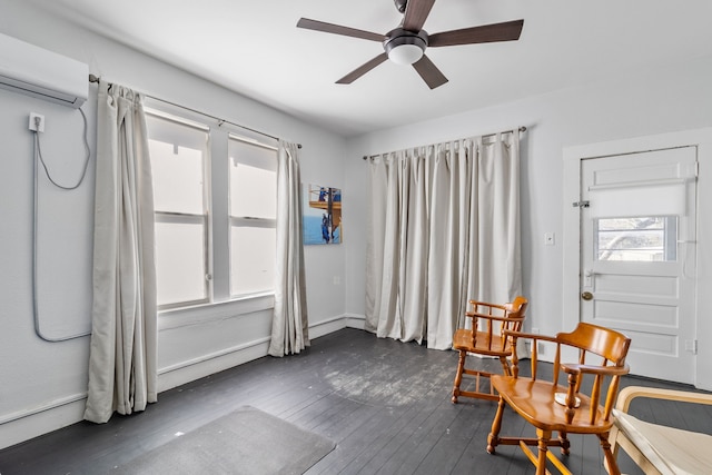 sitting room with dark wood-type flooring, an AC wall unit, and ceiling fan