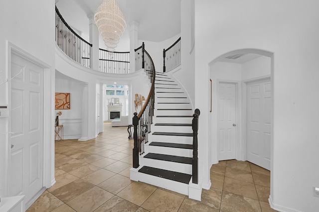 foyer entrance with an inviting chandelier, a towering ceiling, and light tile patterned flooring