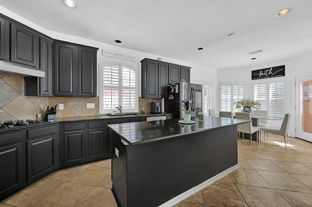 kitchen featuring sink, a center island, stainless steel fridge, black gas cooktop, and decorative backsplash