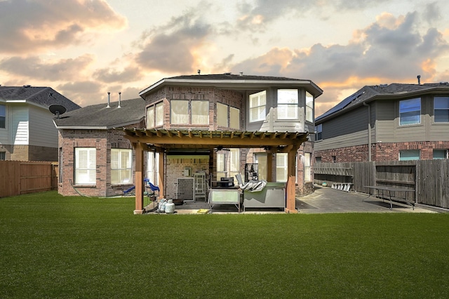 back house at dusk featuring a pergola, a patio area, and a lawn