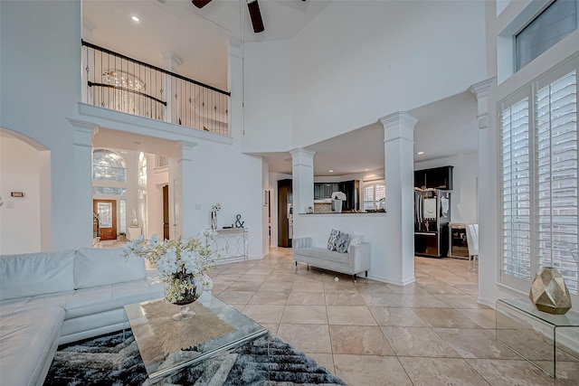 tiled living room with ornate columns, a wealth of natural light, and ceiling fan