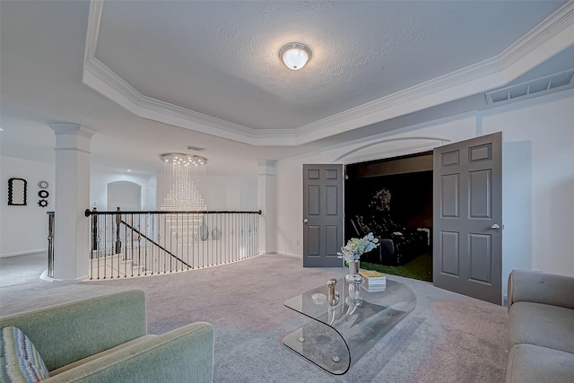 living room featuring ornate columns, a textured ceiling, ornamental molding, carpet flooring, and a tray ceiling