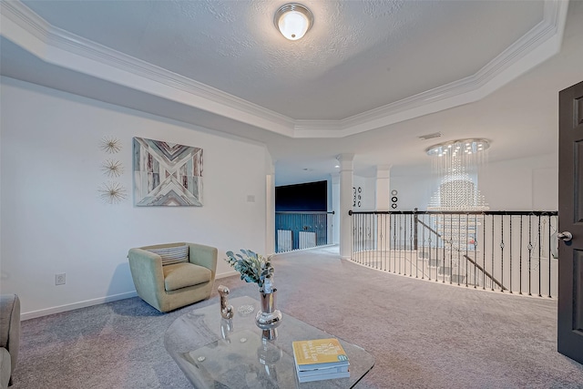 sitting room featuring decorative columns, carpet, ornamental molding, a textured ceiling, and a raised ceiling