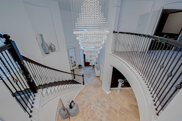 stairs featuring tile patterned flooring, a towering ceiling, and a chandelier