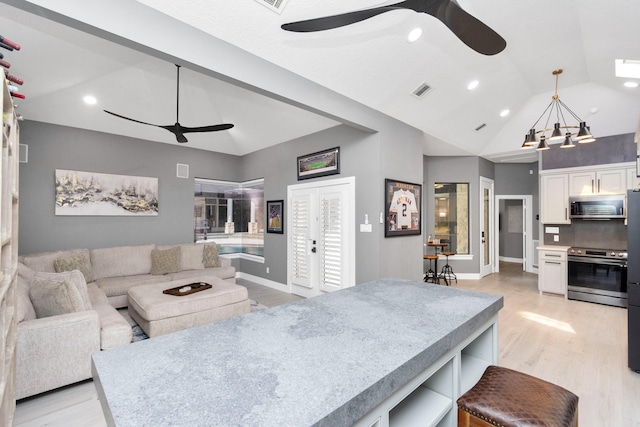 living room with light hardwood / wood-style floors, lofted ceiling, and ceiling fan with notable chandelier