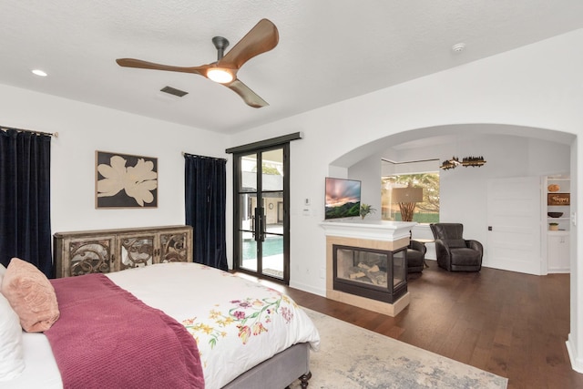 bedroom featuring dark hardwood / wood-style flooring, ceiling fan, access to exterior, and multiple windows