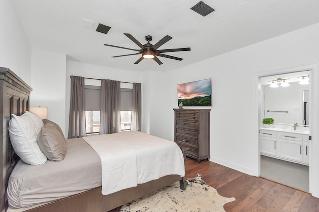 bedroom with ensuite bath, dark wood-type flooring, and ceiling fan