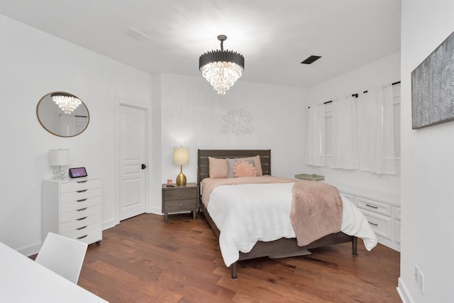 bedroom with a notable chandelier and dark hardwood / wood-style floors