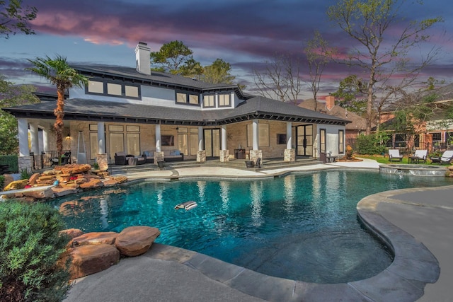 pool at dusk with a patio and an in ground hot tub