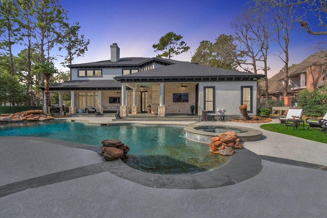 pool at dusk with a patio area, ceiling fan, and an in ground hot tub