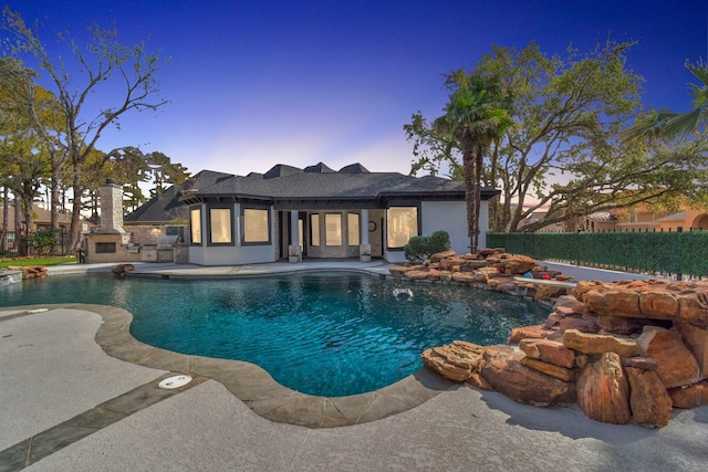 pool at dusk with a patio area