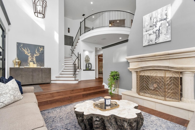 living room featuring a high ceiling, hardwood / wood-style floors, and a tiled fireplace