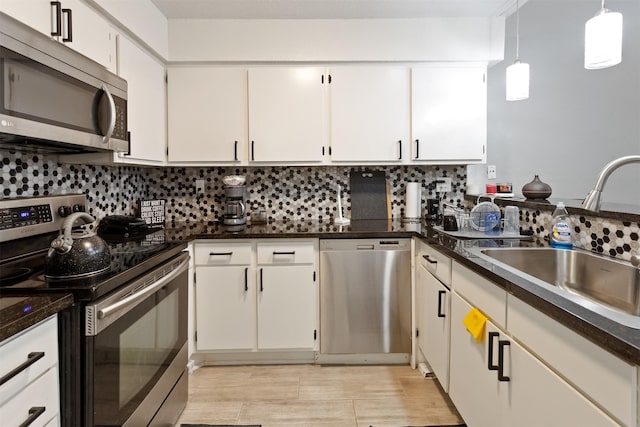 kitchen with decorative light fixtures, decorative backsplash, sink, white cabinetry, and appliances with stainless steel finishes