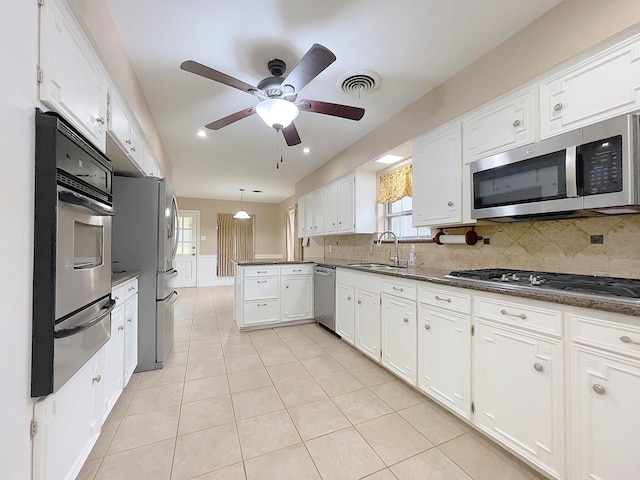 kitchen featuring tasteful backsplash, white cabinets, appliances with stainless steel finishes, and sink