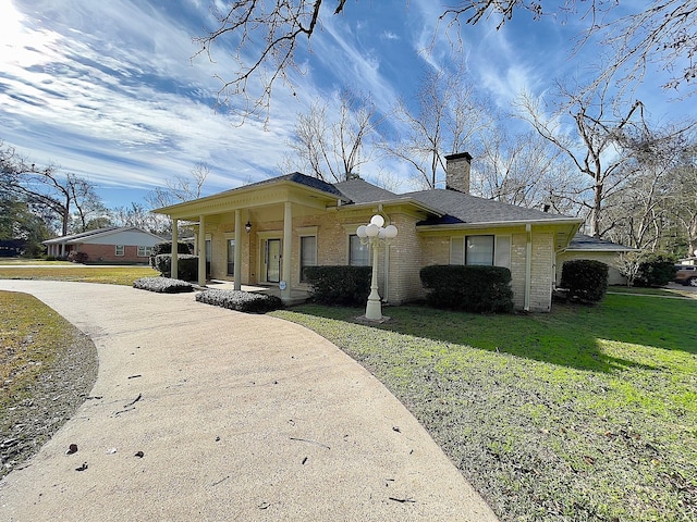 ranch-style house featuring covered porch and a front lawn