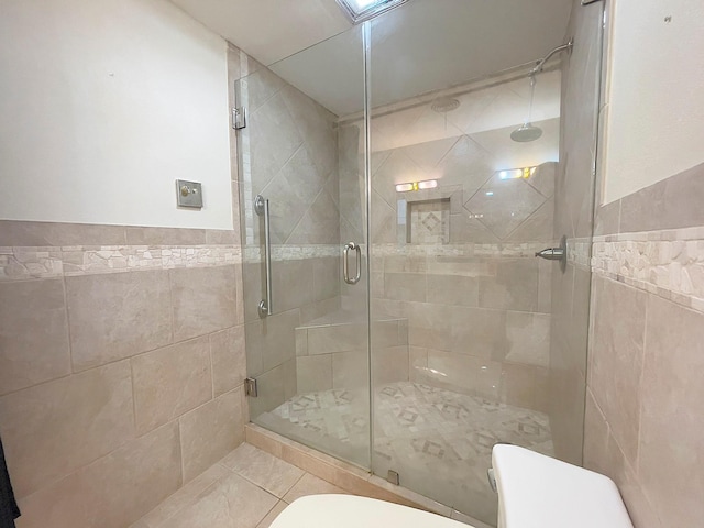 bathroom featuring tile patterned floors, tile walls, toilet, and an enclosed shower