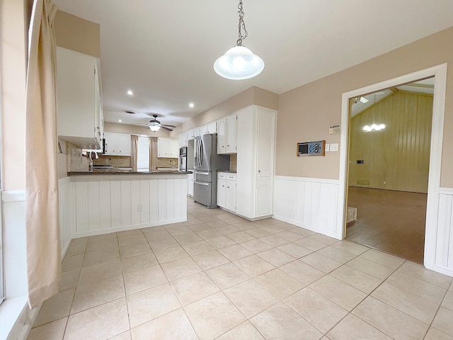 kitchen featuring hanging light fixtures, kitchen peninsula, appliances with stainless steel finishes, and white cabinetry