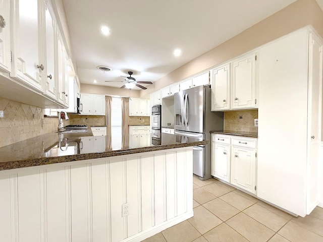 kitchen with white cabinetry, appliances with stainless steel finishes, dark stone countertops, and kitchen peninsula