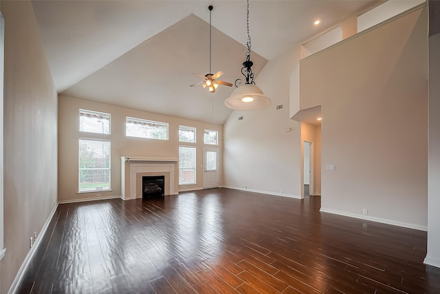 unfurnished living room with high vaulted ceiling, dark wood-type flooring, a ceiling fan, a fireplace, and baseboards