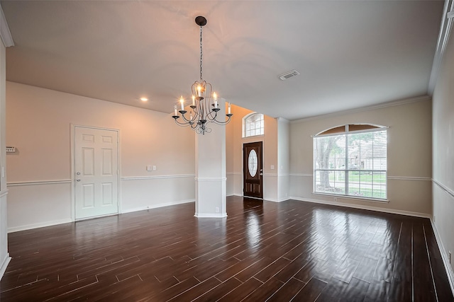 empty room featuring dark wood-style floors, visible vents, baseboards, ornamental molding, and a notable chandelier