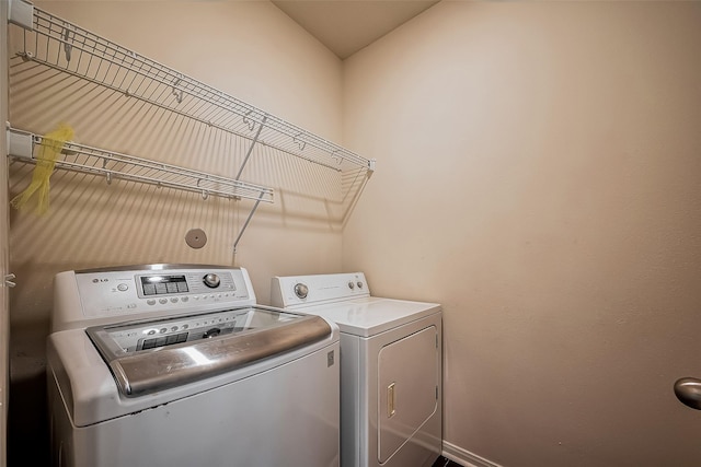 clothes washing area featuring baseboards, independent washer and dryer, and laundry area