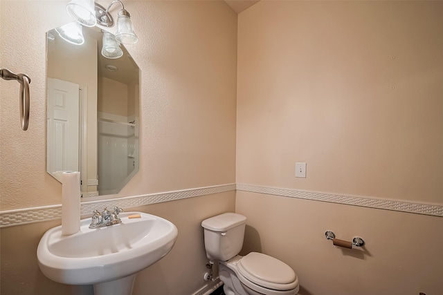 bathroom with a sink, a shower with shower door, and toilet