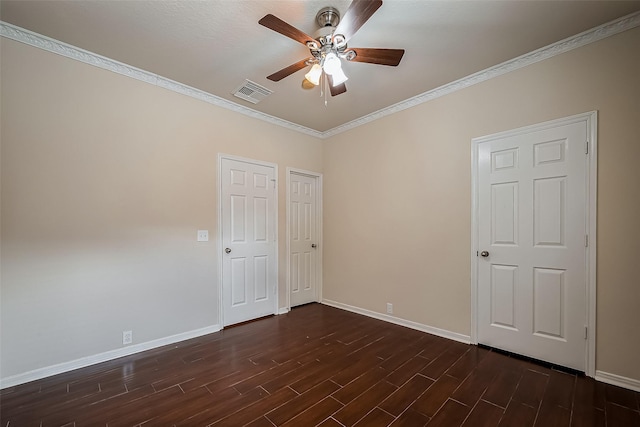 spare room featuring visible vents, ornamental molding, a ceiling fan, dark wood finished floors, and baseboards