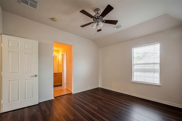 unfurnished bedroom with visible vents, baseboards, dark wood-type flooring, and vaulted ceiling