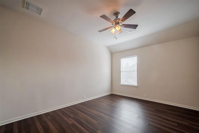 spare room featuring dark wood finished floors, visible vents, lofted ceiling, and baseboards