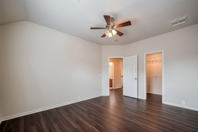 unfurnished bedroom with dark wood-style floors, visible vents, baseboards, a spacious closet, and a closet