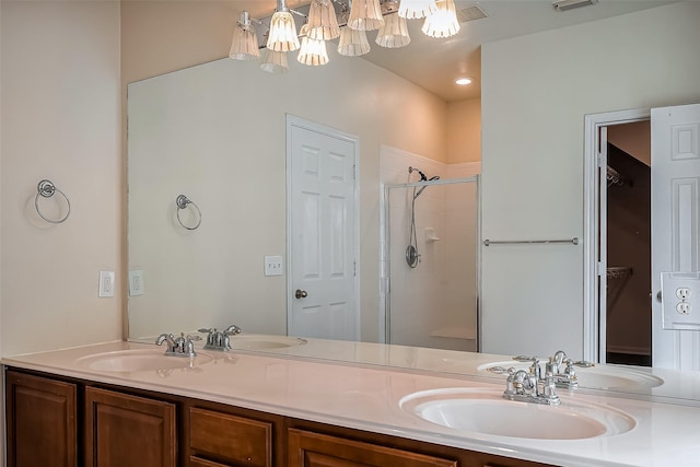 bathroom with a shower stall, an inviting chandelier, and a sink