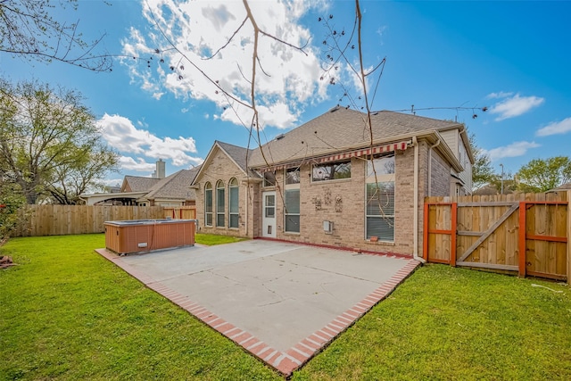 back of house with a gate, a patio, a fenced backyard, a yard, and a hot tub