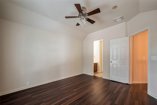 unfurnished bedroom with dark wood finished floors, visible vents, baseboards, and lofted ceiling