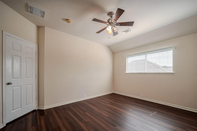 empty room with dark wood-type flooring, visible vents, and lofted ceiling