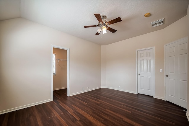 unfurnished bedroom with a spacious closet, dark wood-style floors, visible vents, and baseboards