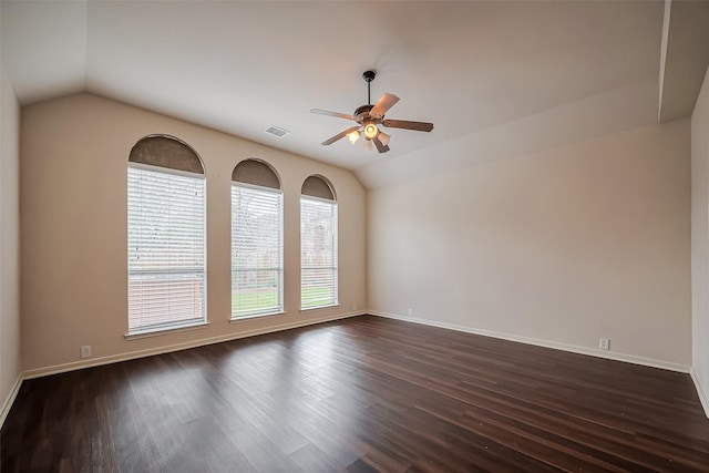 unfurnished room featuring visible vents, dark wood-type flooring, a ceiling fan, baseboards, and vaulted ceiling