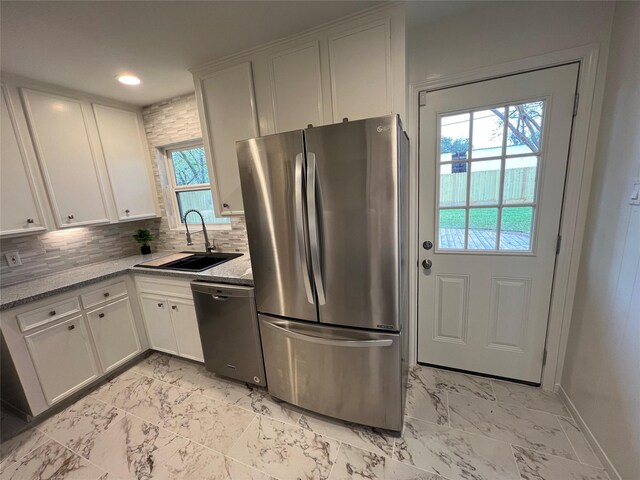 kitchen with stainless steel appliances, sink, white cabinets, decorative backsplash, and light stone countertops