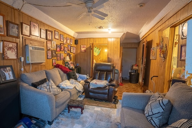 living room with ceiling fan, a textured ceiling, and wooden walls