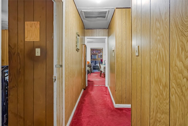 corridor with dark colored carpet and wooden walls