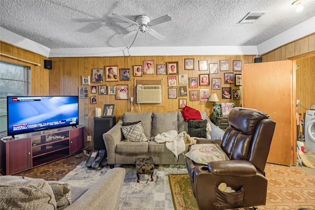 living room featuring ceiling fan, a textured ceiling, a wall mounted AC, and wooden walls