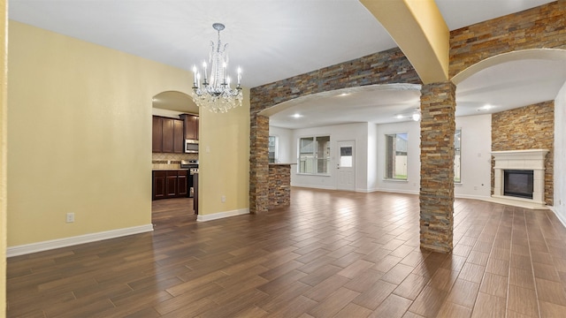 unfurnished living room with a notable chandelier and decorative columns