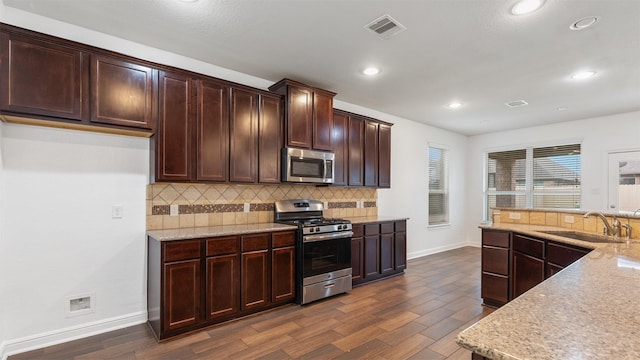 kitchen featuring sink, appliances with stainless steel finishes, light stone counters, and dark hardwood / wood-style floors