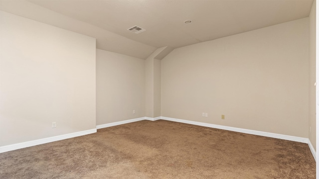 carpeted spare room with vaulted ceiling