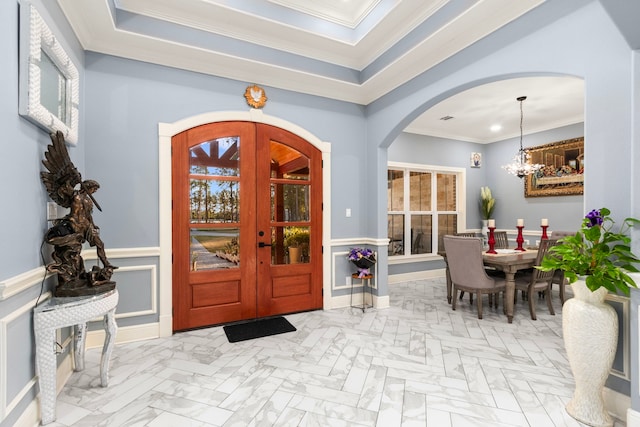 entrance foyer featuring an inviting chandelier, crown molding, and french doors