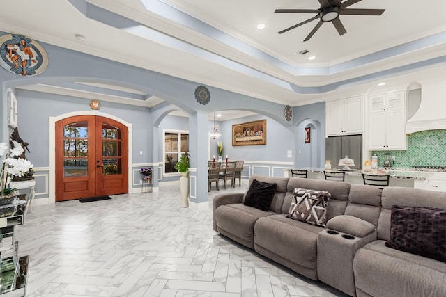 living room featuring ceiling fan, light parquet floors, a tray ceiling, and ornamental molding